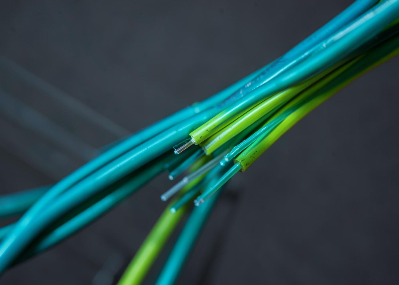 Close-up of teal and green fibre optic cables against a dark grey background